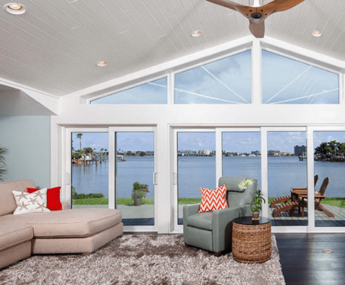 Window and sliding glass door replacement with water front view and custom-shaped windows above the doors.