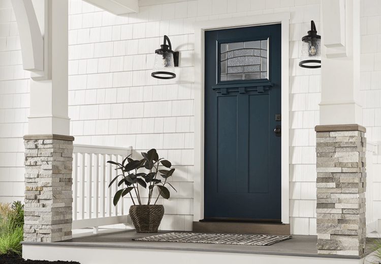 Exterior view of a dark blue craftsman door on a white home