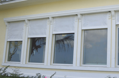 Row of windows with storm fabric partially covering the top of them
