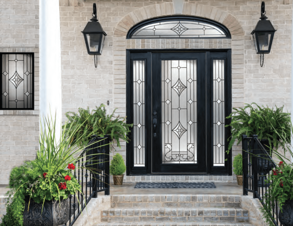 Black front door with decorative glass and sidelites on white brick home.