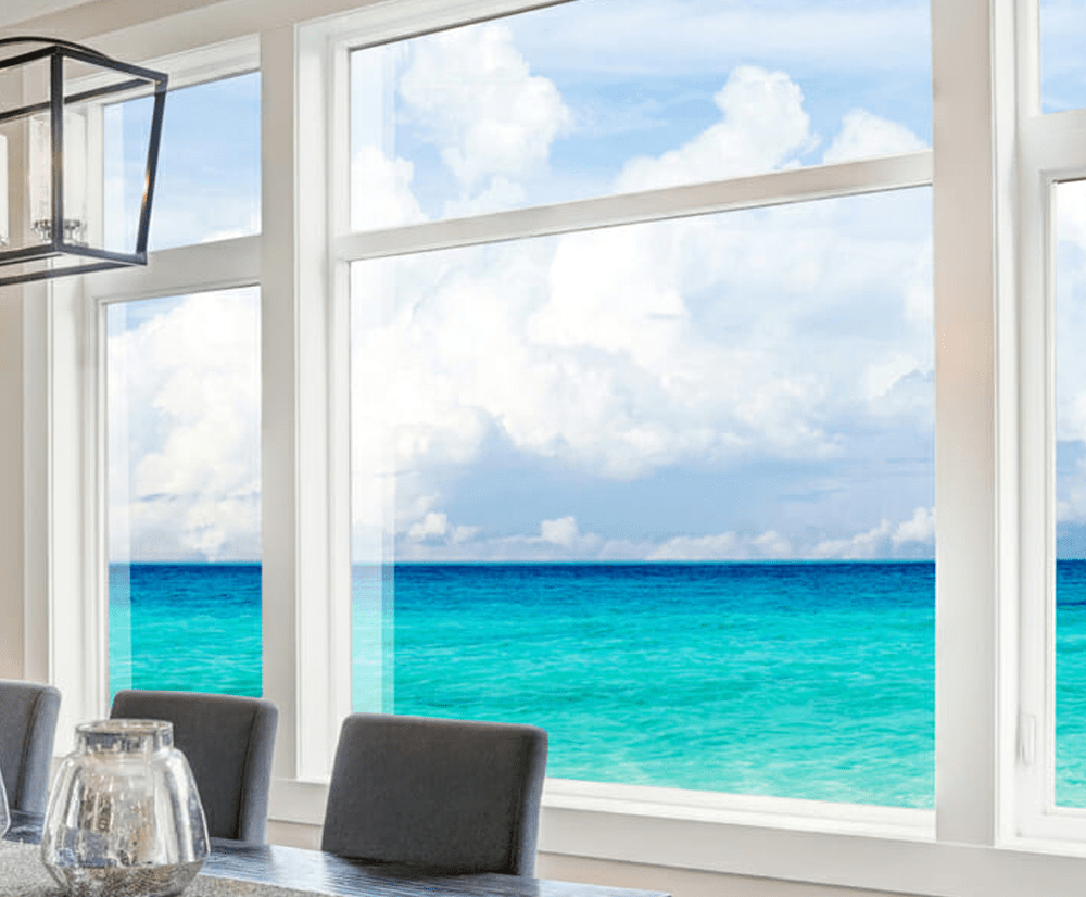 Large white-framed casement window with a view of the sea.