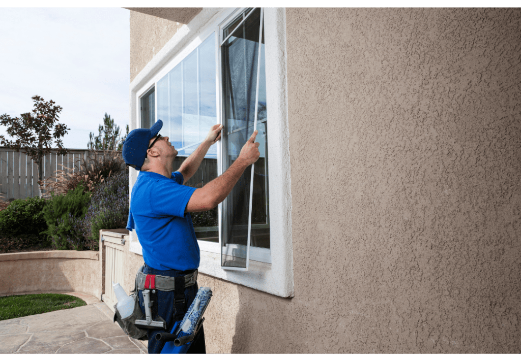 A1 Windows & Doors technician in blue polo shirt and blue cap, installing hurricane-impact windows on home with tan stucco siding.